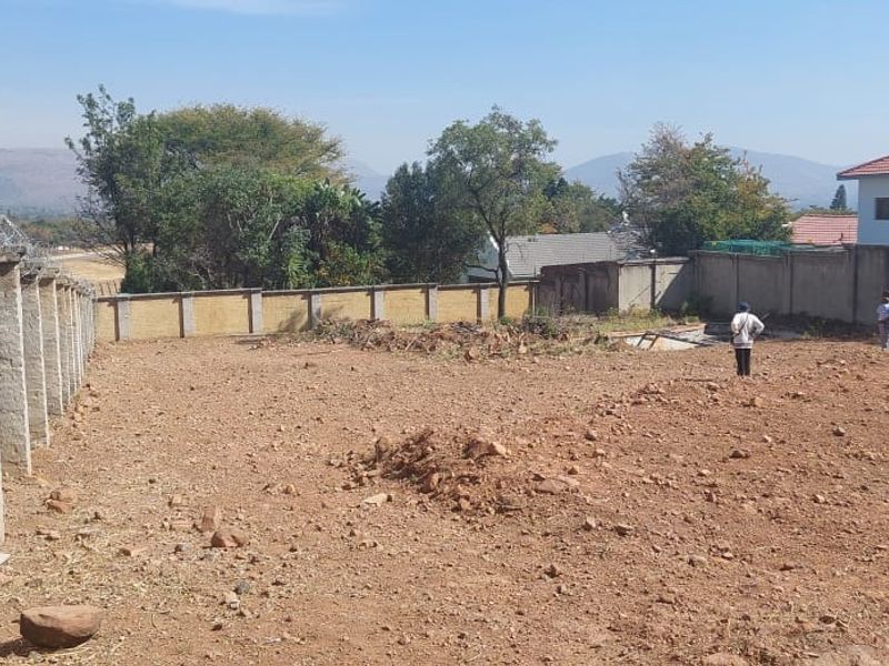 A vacant residential plot featuring a perimeter wall with security razor wire, offering a clear space for future development.