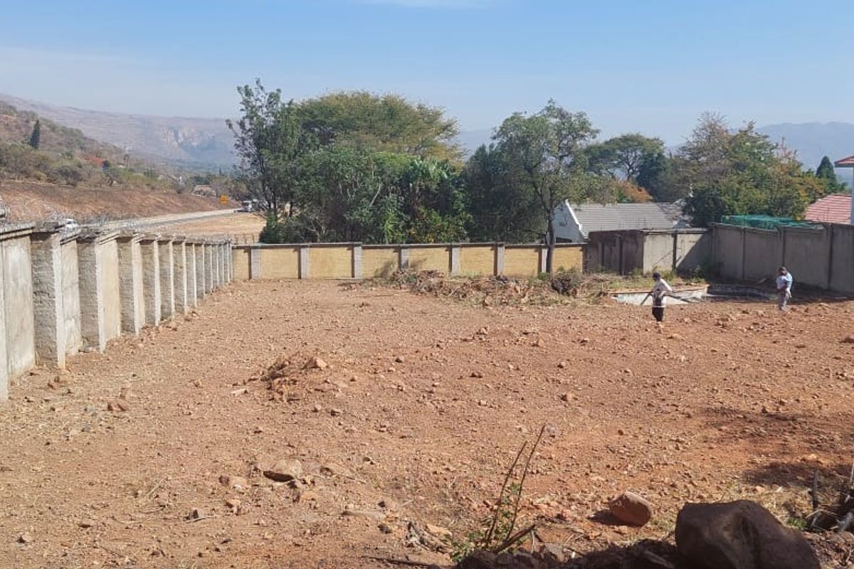 A vacant residential plot featuring a perimeter wall with security razor wire and an existing swimming pool structure.