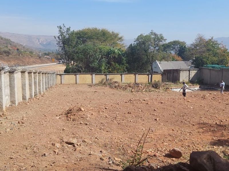 A vacant residential plot featuring a perimeter wall with security razor wire and an existing swimming pool structure.