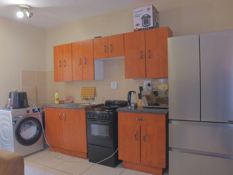 A functional kitchen area featuring laminate cabinetry, a built-in oven, hob, and tiled backsplash, with integrated space for laundry appliances.