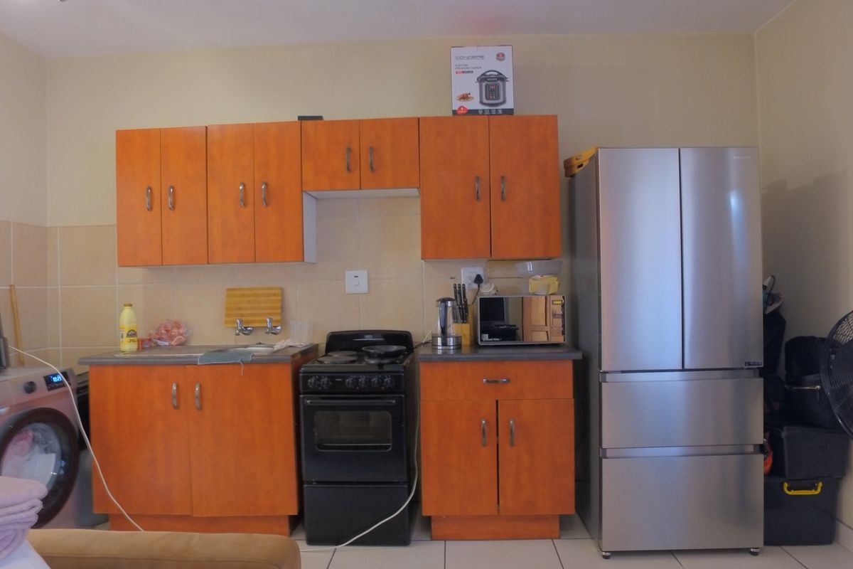 A functional kitchen featuring wood-look cabinetry, a tiled backsplash, and a freestanding stove, providing essential cooking and storage space.