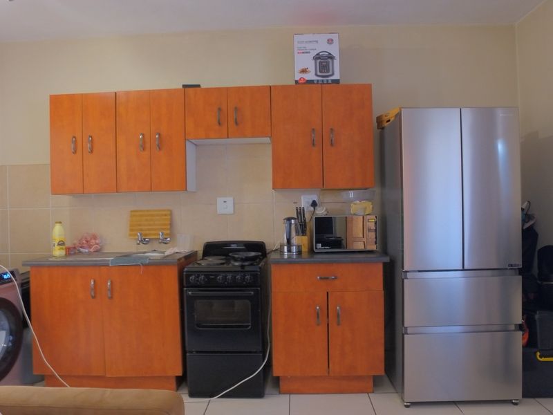 A functional kitchen featuring wood-look cabinetry, a tiled backsplash, and a freestanding stove, providing essential cooking and storage space.