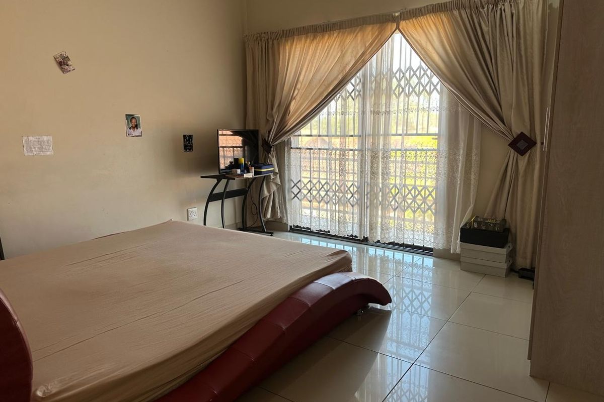 A bedroom featuring tiled flooring, a built-in wardrobe, and a sliding glass door with a security gate leading to an outdoor area.