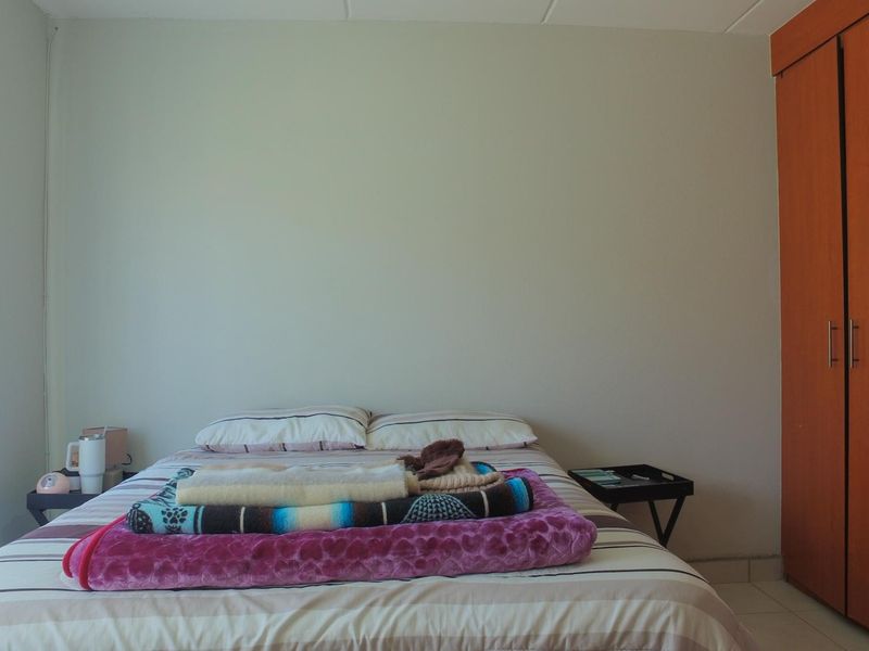 A bedroom featuring tiled flooring and a built-in wooden wardrobe, providing functional storage space.