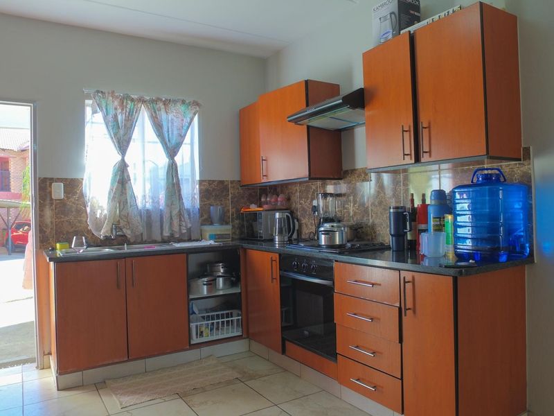 A functional kitchen featuring wood-look laminate cabinetry, granite countertops, a built-in oven, and an extractor fan, with direct access to the exterior.