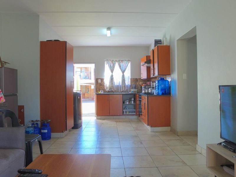 Open-plan living and kitchen area featuring tiled flooring and functional built-in cabinetry with a direct access point to the exterior.