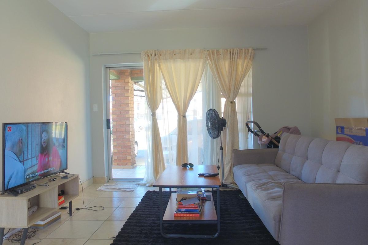 A living room featuring tiled flooring and a sliding glass door providing access to the exterior.