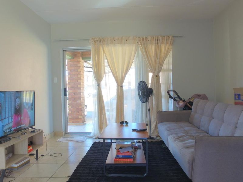 A living room featuring tiled flooring and a sliding glass door providing access to the exterior.