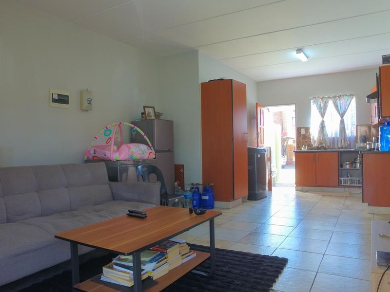 Open-plan living area featuring tiled flooring and a functional kitchen with built-in cabinetry and an extractor fan.
