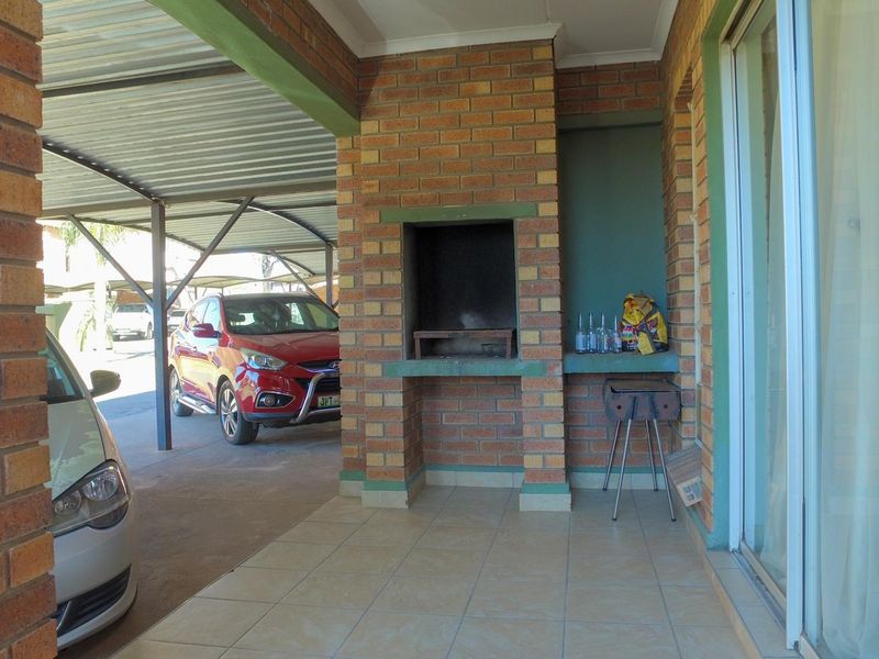 Covered patio area featuring a built-in brick braai, tiled flooring, and direct access to the living space via sliding glass doors.
