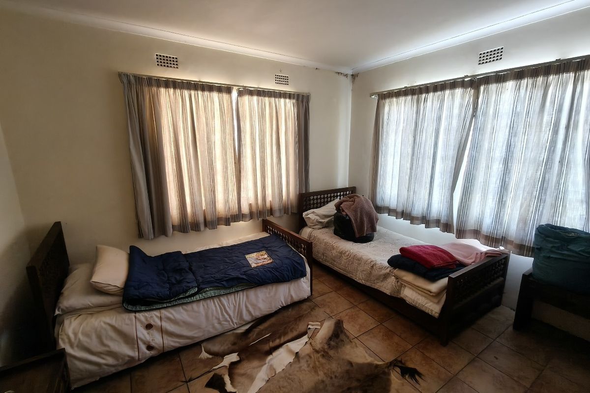 A bedroom featuring tiled flooring and dual windows with curtain rails. Note visible water staining on the ceiling corner requiring attention.