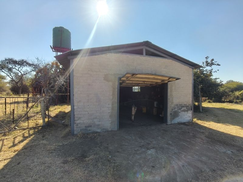 A detached farm garage featuring a metal roof and an elevated water tank, set within a rural landscape.