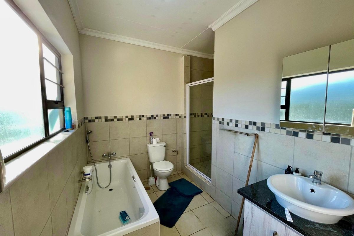 A functional bathroom featuring a bathtub, separate shower enclosure, vanity with basin, and neutral wall tiling.