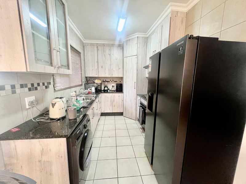 A functional kitchen featuring light wood-grain cabinetry, granite countertops, tiled backsplash, and integrated appliances, offering a practical layout for daily meal preparation.