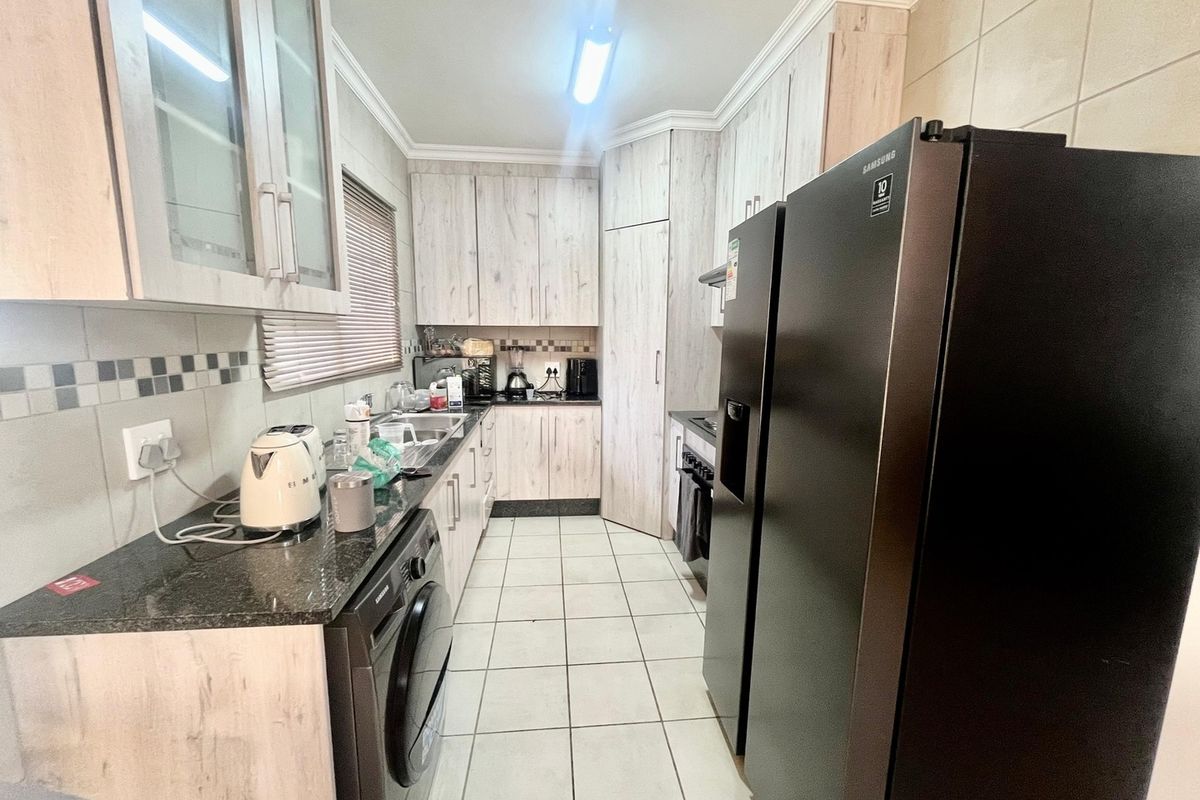 A functional kitchen featuring light wood-grain cabinetry, granite countertops, tiled backsplash, and integrated appliances, offering a practical layout for daily meal preparation.