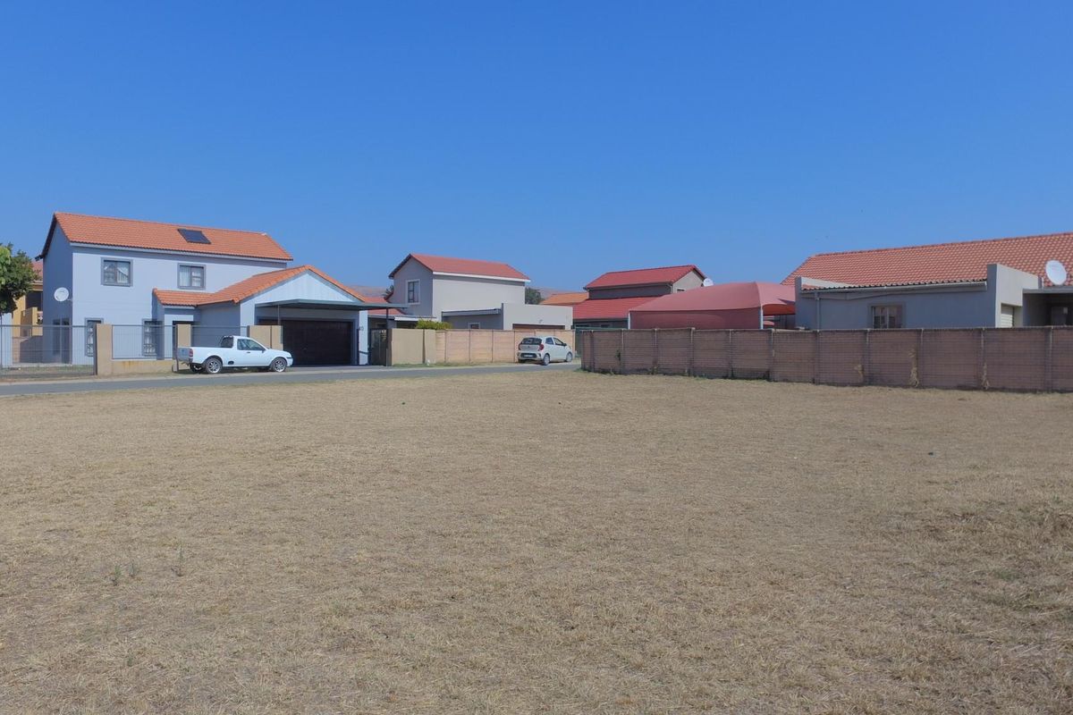 A vacant residential plot situated in a developed neighborhood, featuring level ground and established boundary walls.