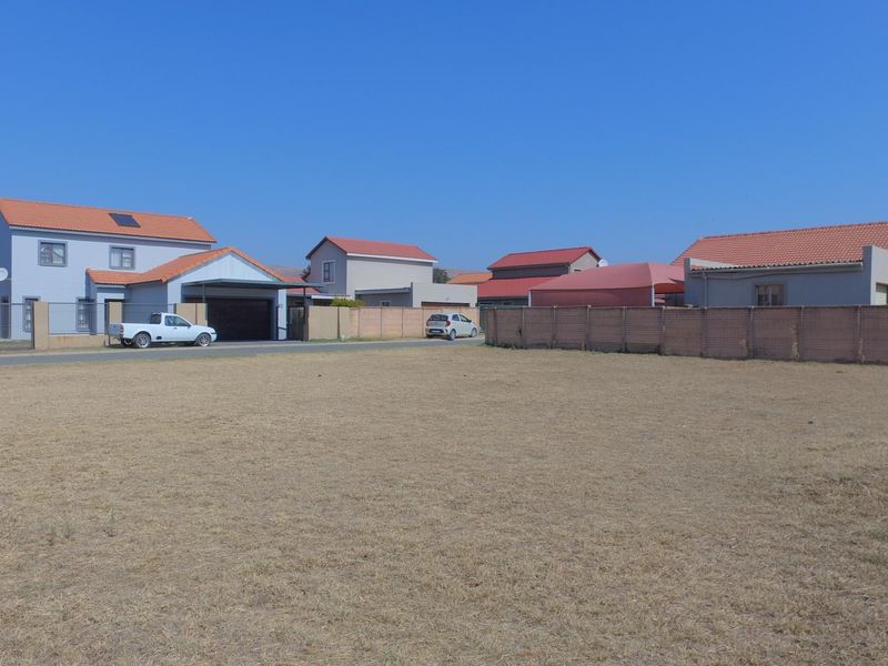 A vacant residential plot situated in a developed neighborhood, featuring level ground and established boundary walls.