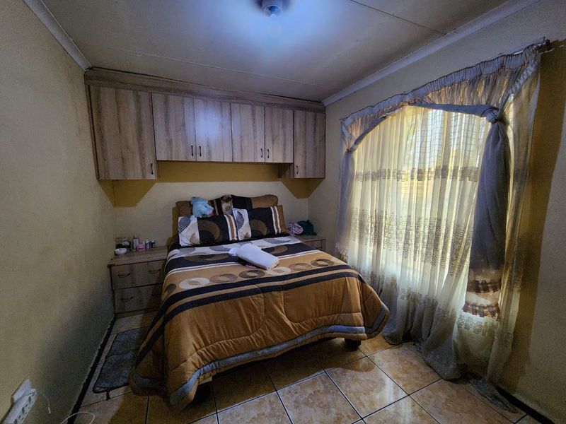 A bedroom featuring built-in cupboards and tiled flooring, offering a functional space with potential for cosmetic updates.