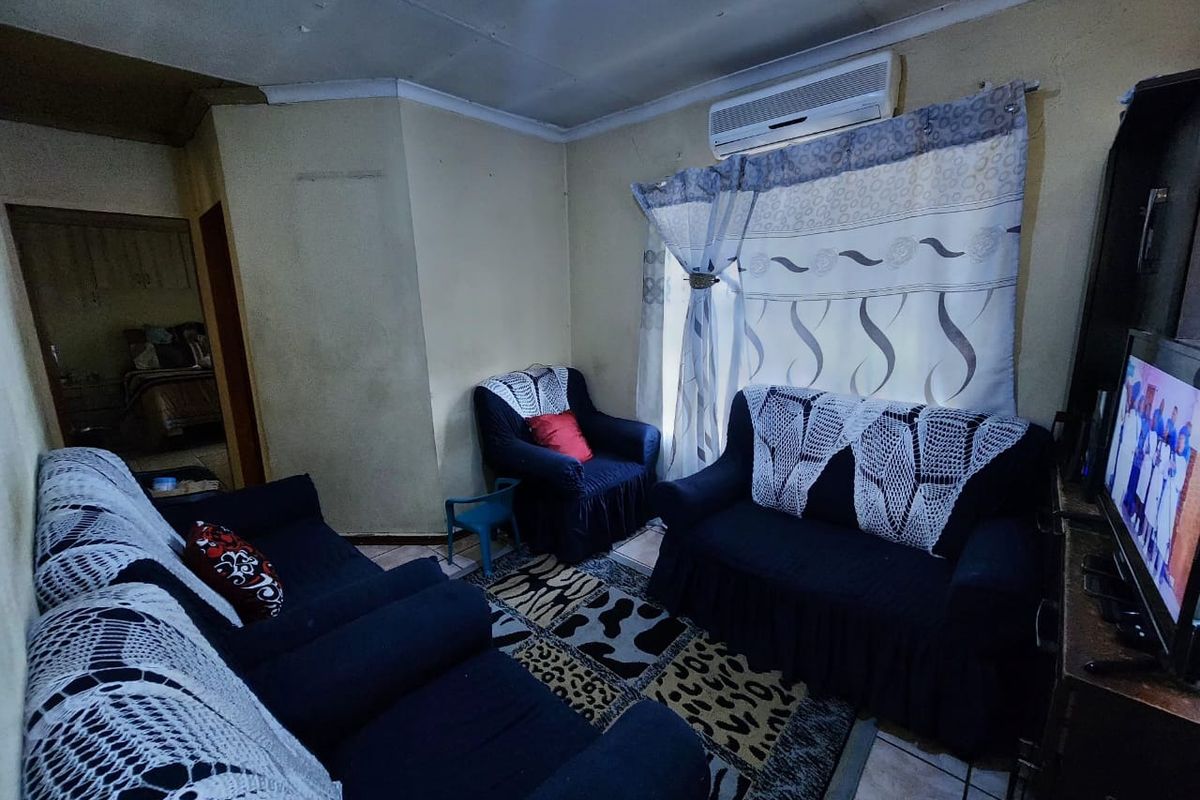 A living room featuring tiled flooring, a wall-mounted air conditioning unit, and coved ceiling detailing.
