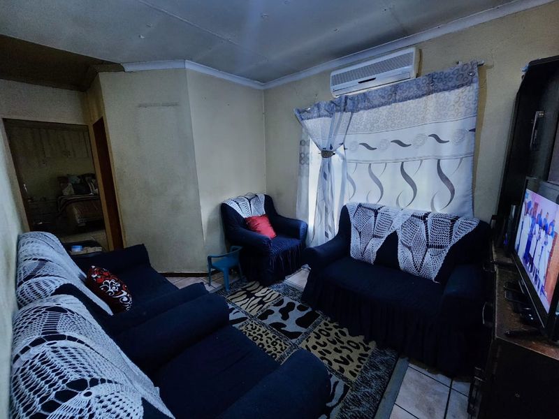 A living room featuring tiled flooring, a wall-mounted air conditioning unit, and coved ceiling detailing.