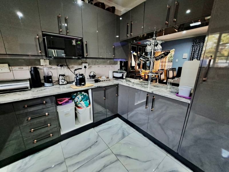 Modern kitchen featuring high-gloss grey cabinetry, marble-effect countertops, and matching floor tiles with a clean, contemporary finish.