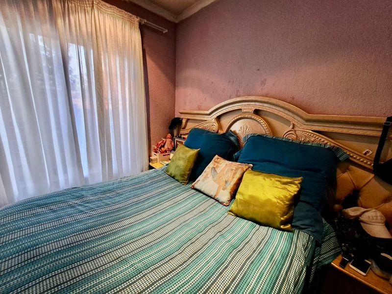 A bedroom featuring a window with curtain rails and coving, showing signs of wall staining and wear requiring cosmetic attention.