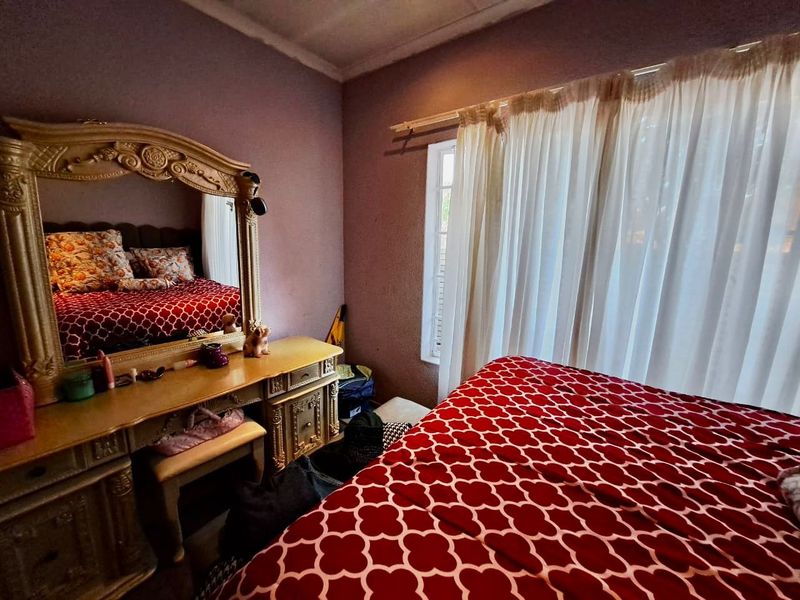 A bedroom featuring a window with a curtain rod and textured wall finishes, requiring cosmetic updates to improve the overall aesthetic.