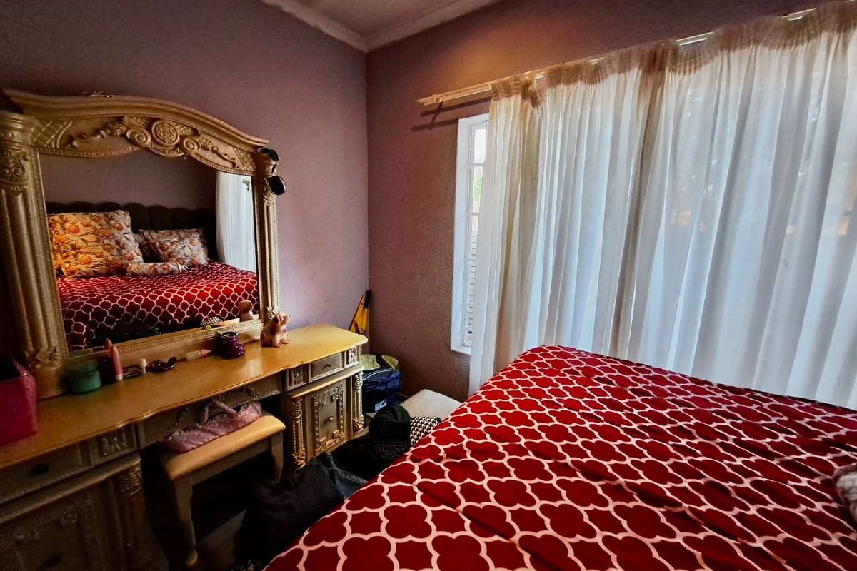 A bedroom featuring a window with a curtain rod and textured wall finishes, requiring cosmetic updates to improve the overall aesthetic.