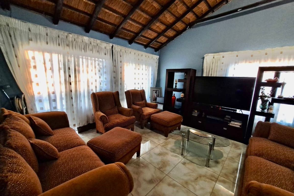 Spacious living room featuring a high vaulted thatched ceiling with exposed timber beams and neutral tiled flooring.