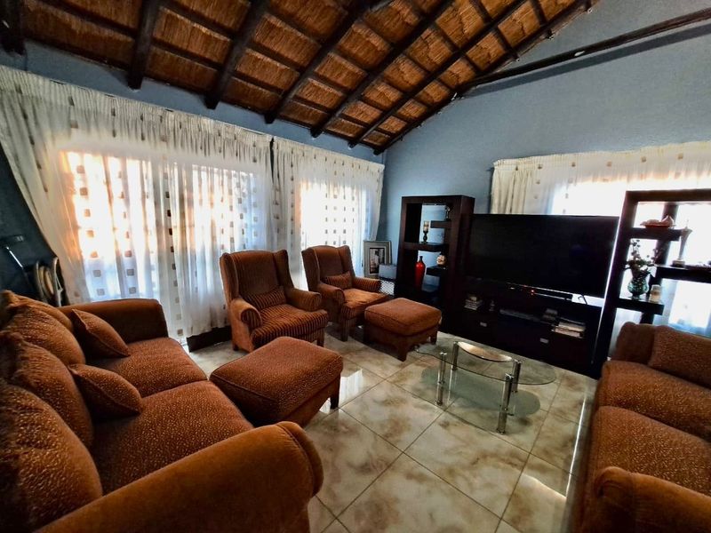 Spacious living room featuring a high vaulted thatched ceiling with exposed timber beams and neutral tiled flooring.