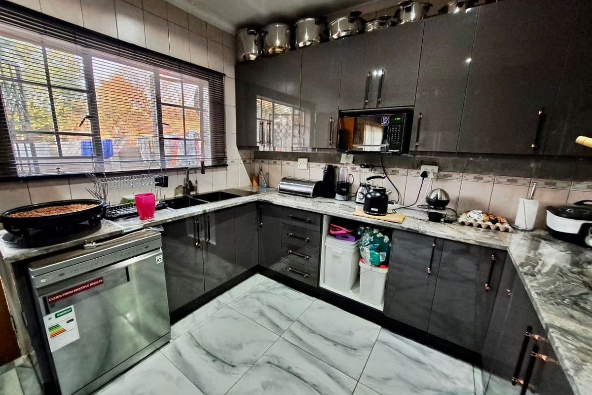 Modern kitchen featuring high-gloss grey cabinetry, marble-effect floor tiles, stone-look countertops, and integrated appliances including a built-in microwave and dishwasher.