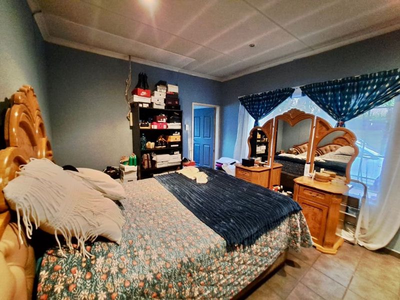 A bedroom featuring tiled flooring and a drop ceiling, currently showing signs of wear including exposed wall wiring.