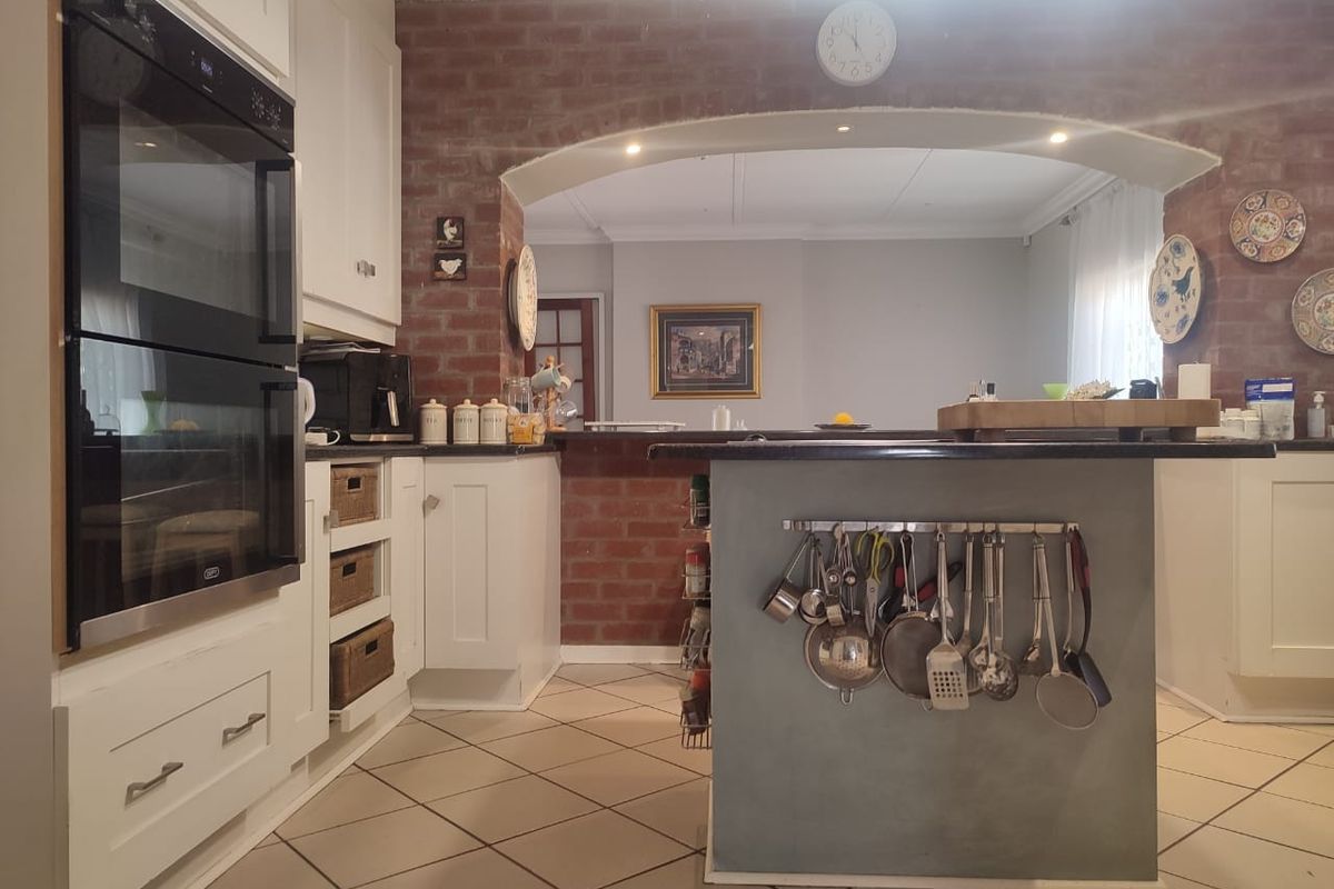 A functional kitchen featuring a central island, built-in double oven, and a distinctive exposed brick archway connecting to the adjacent living space.