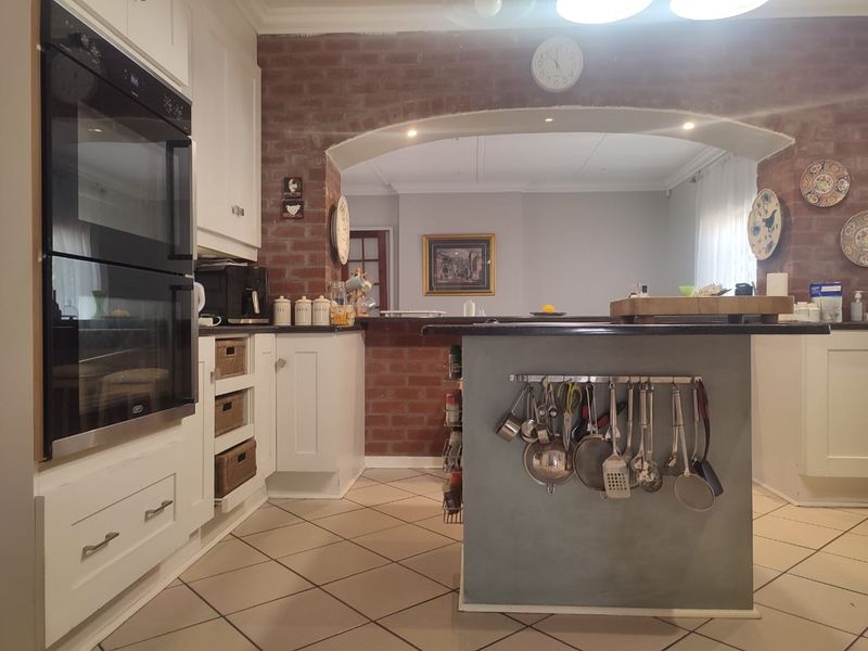 A functional kitchen featuring a central island, built-in double oven, and a distinctive exposed brick archway connecting to the adjacent living space.