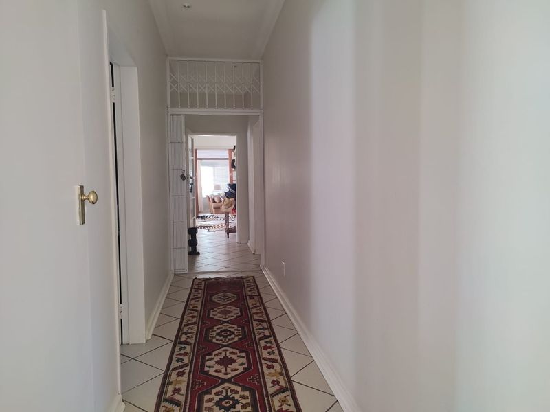 A bright, tiled hallway featuring a security gate and recessed lighting, providing access to the main living areas of the home.