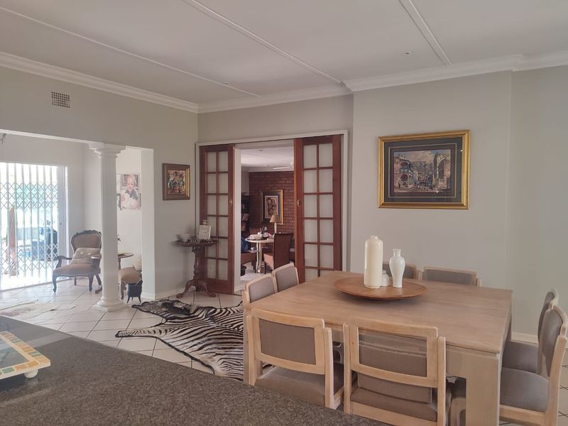 Spacious open-plan dining area featuring elegant crown molding, tiled flooring, and classic wooden sliding doors leading to an adjacent room.