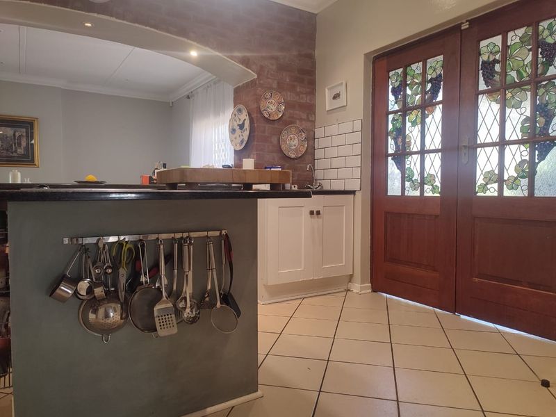Kitchen area featuring a central island, exposed brick accent wall, subway tile backsplash, and decorative stained glass double doors leading to the exterior.