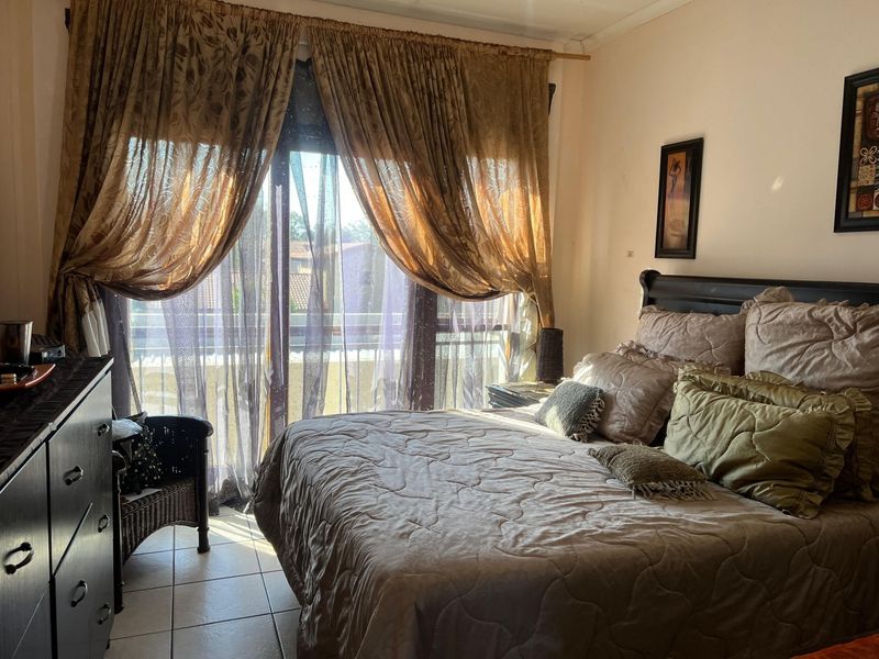 A bedroom featuring tiled flooring and a sliding glass door providing access to an outdoor area, allowing for natural light.