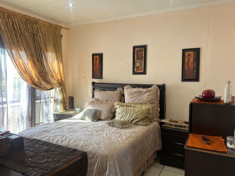 A well-lit bedroom featuring tiled flooring, recessed ceiling lights, and a large sliding glass door providing access to an outdoor area.
