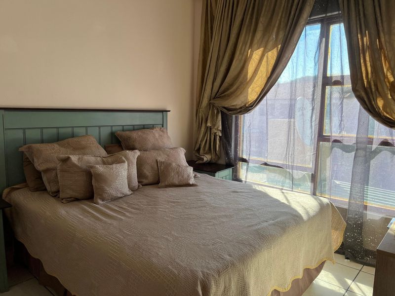 A bedroom featuring tiled flooring and a large window that allows for natural light.
