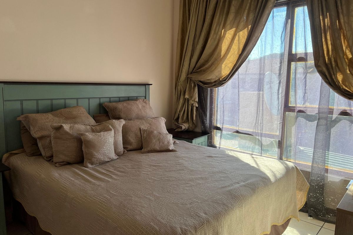 A bedroom featuring tiled flooring and a large window that allows for natural light.