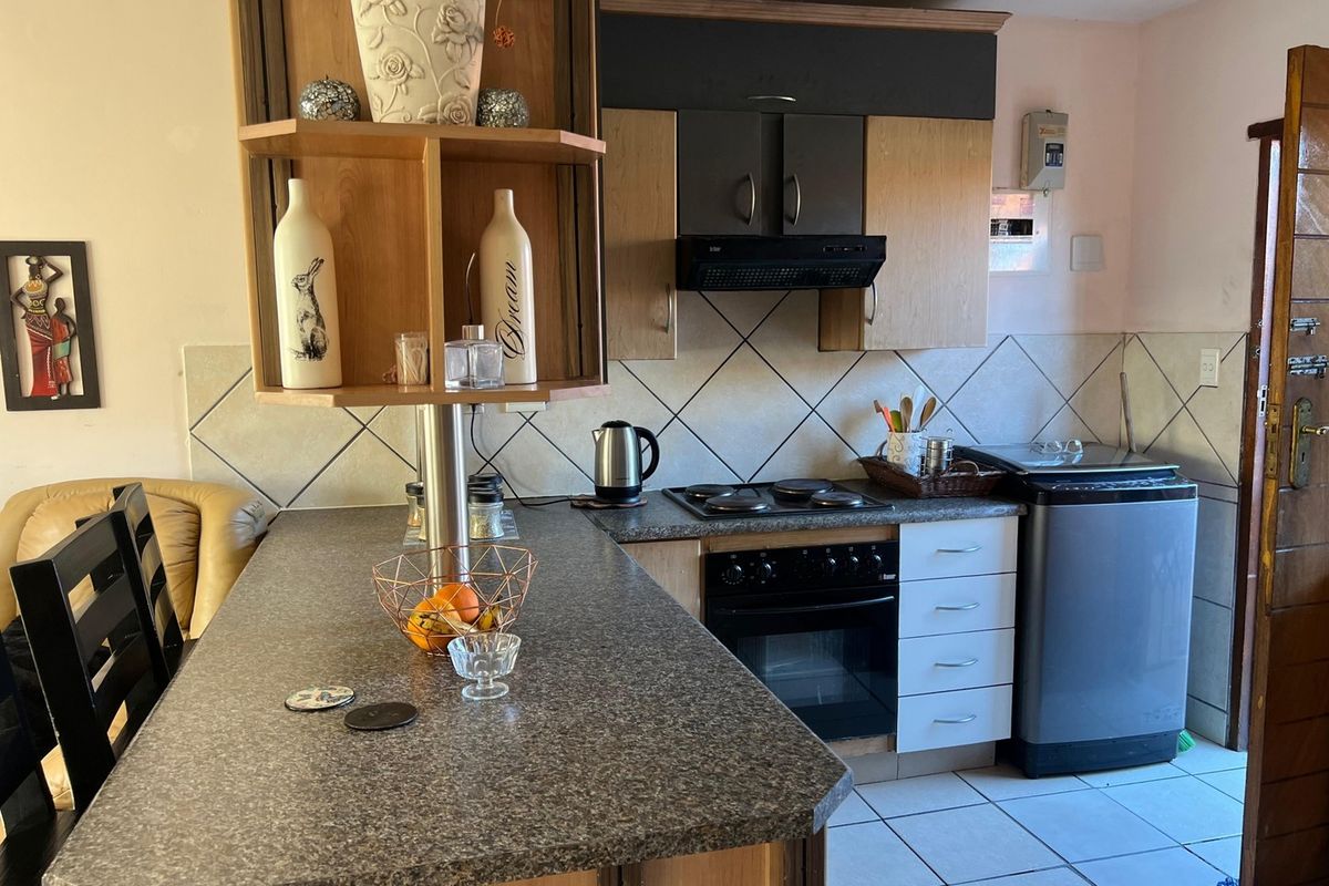 A functional kitchen featuring laminate countertops, built-in oven, electric hob, extractor fan, and tiled backsplash with ample cabinetry.
