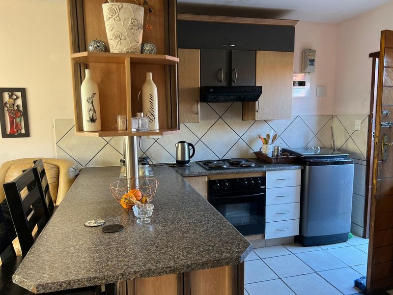 A functional kitchen featuring laminate countertops, built-in oven, electric hob, extractor fan, and tiled backsplash with ample cabinetry.