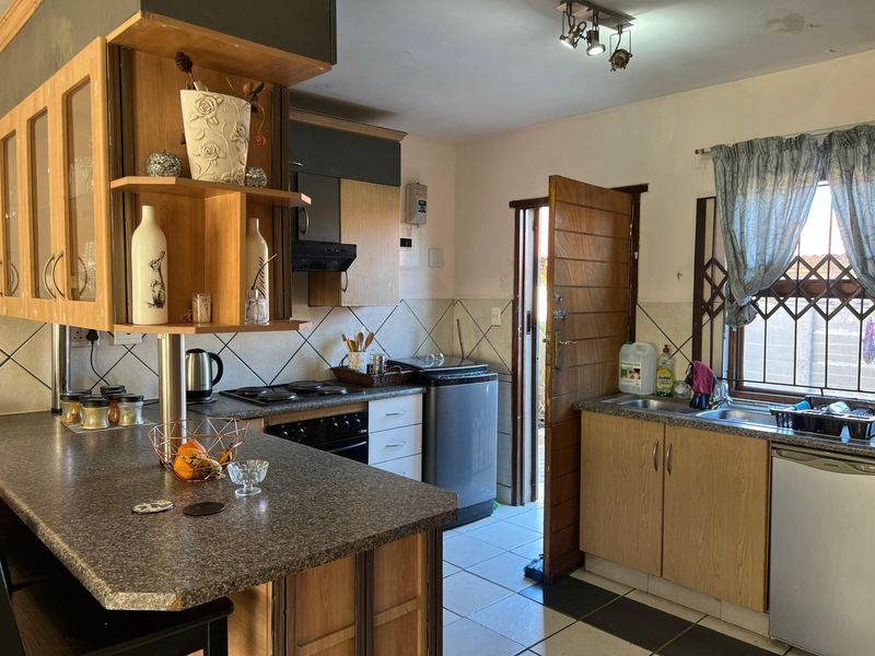 A functional kitchen featuring laminate cabinetry, a built-in oven with hob, tiled backsplash, and direct access to an outdoor area.
