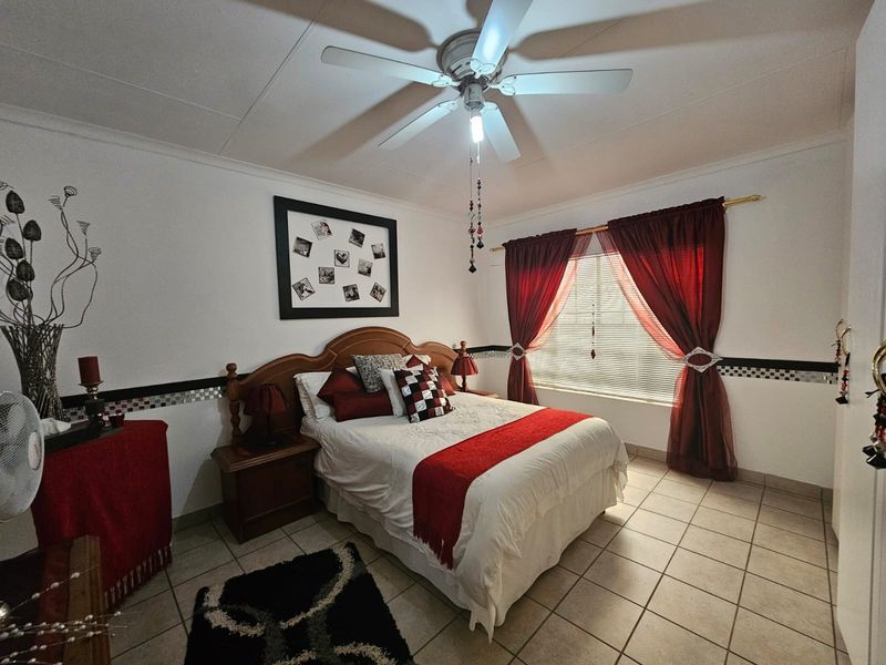 A bedroom featuring tiled flooring, a ceiling fan, and window treatments.