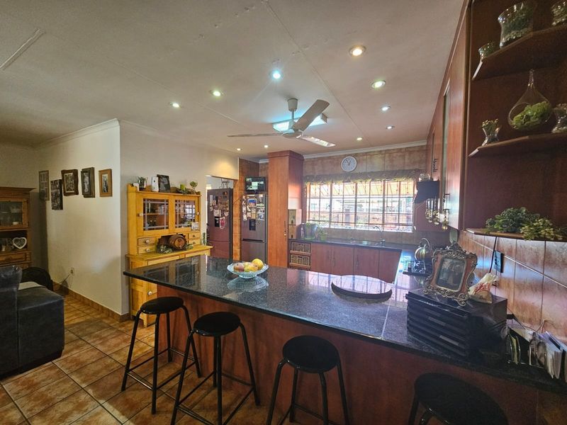 Open plan kitchen featuring a granite island, wooden cabinetry, tiled flooring, and recessed lighting, creating a functional and connected living space.