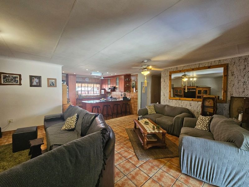 Spacious open-plan living area featuring tiled flooring, a central kitchen island, and integrated cabinetry, creating a functional and connected family living space.