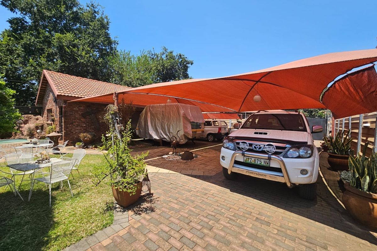 Rear exterior area featuring brick paving, a large orange shade sail structure, and face brick building facade.
