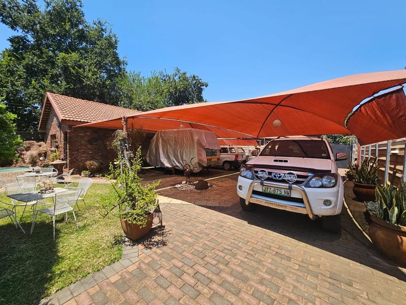 Rear exterior area featuring brick paving, a large orange shade sail structure, and face brick building facade.