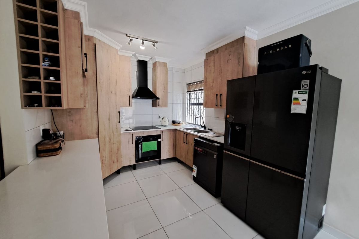 Modern kitchen featuring light wood-finish cabinetry, tiled flooring, built-in oven, electric hob, and a dedicated wine rack for convenient storage.